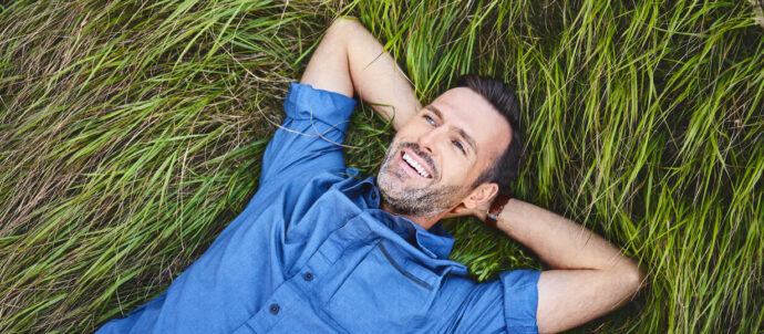 Relaxed happy man lying in grass